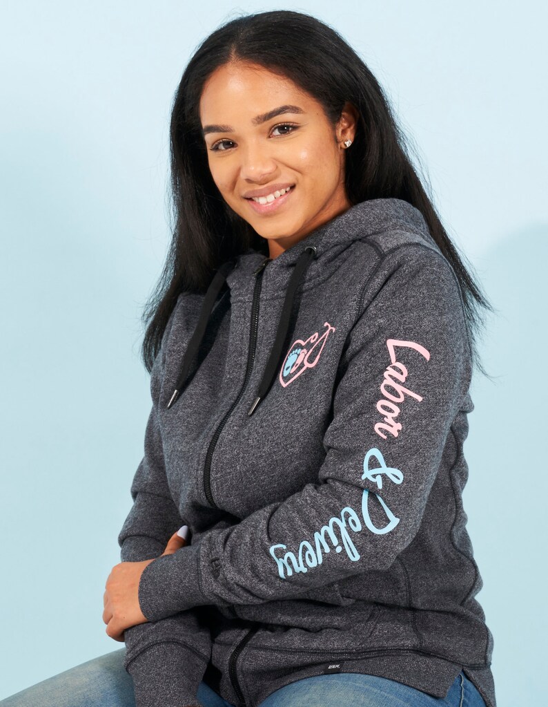 May include: A dark gray zip-up hoodie with a pink and blue graphic on the front and the text "Labor & Delivery" in blue and pink on the sleeve.
