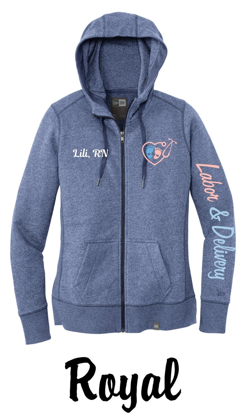 May include: A blue heather zip-up hoodie with a white embroidered heart with baby footprints and a stethoscope. The text "Lili, RN" is embroidered on the left chest and "Labor & Delivery" is embroidered on the right sleeve.