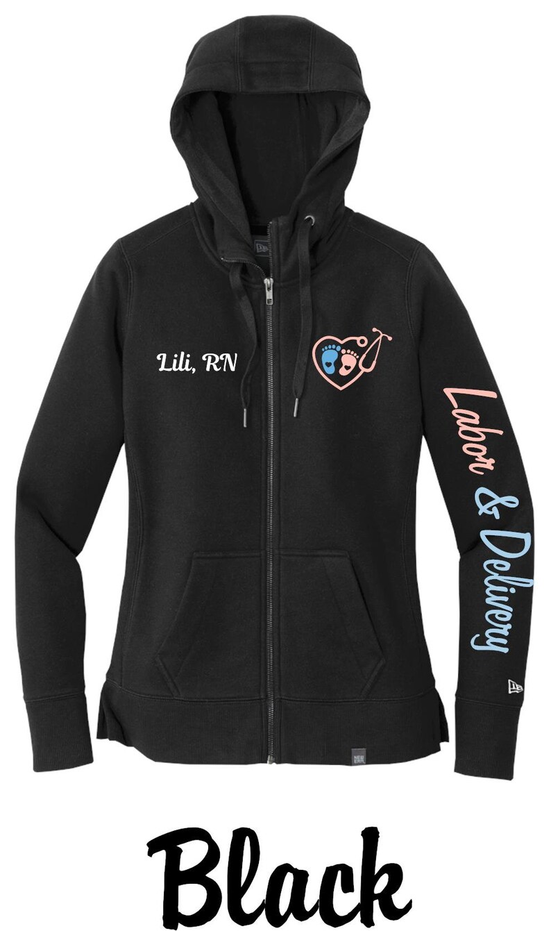May include: Black zip-up hoodie with a white embroidered heart design featuring two footprints and a stethoscope. The text "Lili, RN" is embroidered on the left chest and "Labor & Delivery" is printed on the right sleeve.