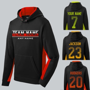May include: Black hoodie with red and yellow side panels. The front features the text "TEAM NAME" in white with a red stripe underneath. The back features a customizable name and number in yellow.