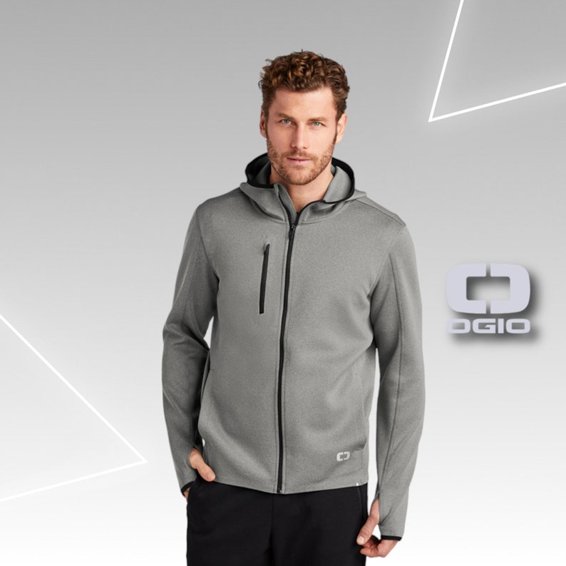 Puede incluir: Una sudadera gris con capucha, cremallera negra y ribetes negros. La sudadera tiene un peque&ntilde;o logotipo en el pecho izquierdo y un logotipo m&aacute;s grande en el lado derecho de la prenda. El logotipo es una letra estilizada "O" con un cuadrado en su interior.