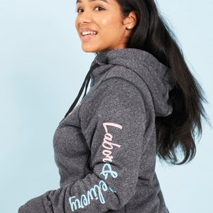 May include: A dark gray hooded sweatshirt with the words "Labor & Delivery" printed on the sleeve in pink and blue lettering.