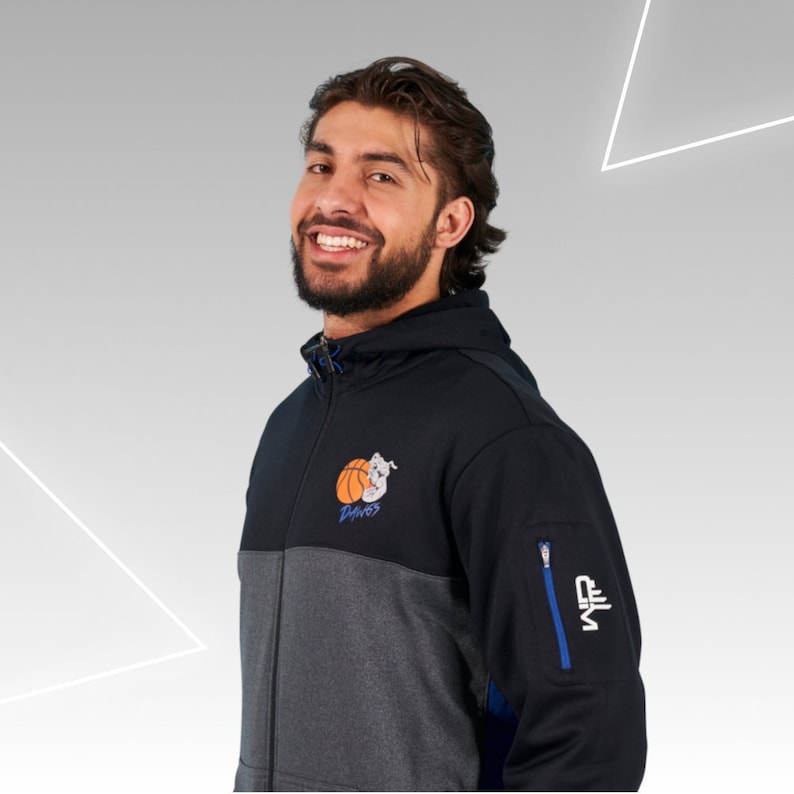 May include: A black and gray zippered hoodie with a basketball and the word "Dinosaurs" on the front. The hoodie has a blue zipper and a blue zippered pocket on the right sleeve. The text "NFL" is on the pocket.