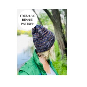 Könnte beinhalten: Eine Person trägt eine blaue und orange gestreifte Mütze mit dem Text "Fresh Air Beanie Pattern" auf einem weißen Kreis.