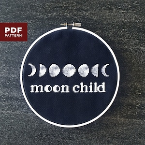 Peut inclure: Un cerceau de broderie noir avec une broderie blanche d'un croissant de lune, d'une pleine lune et de phases de lune. Le texte "moon child" est brodé sous les lunes.