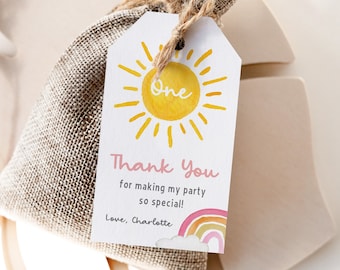 May include: A white thank you tag with a yellow sun and the word "One" in pink. The tag also has the text "Thank You for making my party so special! Love, Charlotte" and a rainbow with clouds.