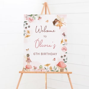Pode incluir: Bem-vindo ao cartaz do 6&ordm; anivers&aacute;rio de Olivia com fundo rosa e borda floral. O cartaz apresenta duas fadas, cogumelos e um sapo.