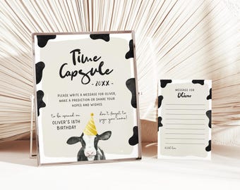 May include: A framed time capsule sign and a matching message card. The sign features a cow illustration wearing a party hat and the text "Time Capsule - 20XX". The message card is for Oliver.