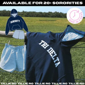 May include: A navy blue hoodie with the white text TRI DELTA and a matching pair of blue and white striped shorts. The hoodie features a blue and white striped interior lining in the hood. The text AVAILABLE FOR 20+ SORORITIES is visible.