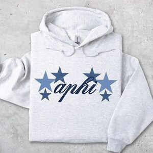 May include: A gray hooded sweatshirt with a blue and gold star design and the text "aphi" in blue cursive.