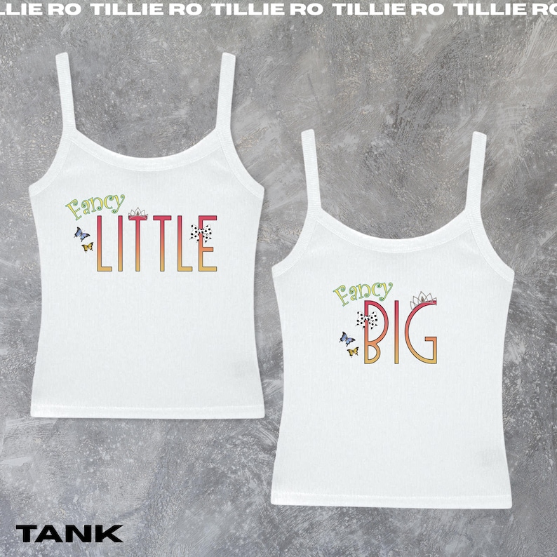 Pode incluir: Duas camisetas brancas com as palavras "Fancy LITTLE" e "Fancy BIG" em letras coloridas. As camisetas t&ecirc;m al&ccedil;as finas e s&atilde;o decoradas com borboletas e desenhos florais. A palavra "TANK" est&aacute; na parte inferior.