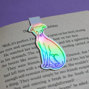 Op de afbeelding: Een regenboogkleurige, iriserende bladwijzer met het silhouet van een windhond. De bladwijzer is gemaakt van een dun, flexibel materiaal en is ontworpen om tussen de pagina's van een boek te passen.