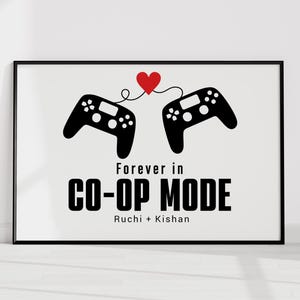 May include: Framed print featuring two black game controllers connected by a red heart. The text "Forever in CO-OP MODE" is displayed in bold, black letters, with names below. A modern, minimalist design.