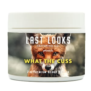 May include: A white jar with a yellow and black label featuring a fox and the text "Last Looks Grooming Co. presents What the Cuss 2 oz Premium Beard Butter".