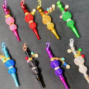 May include: Ten colorful metal smoking pipes with decorative charms. Each pipe has two round beads with rhinestones. The pipes are numbered 1 through 8.