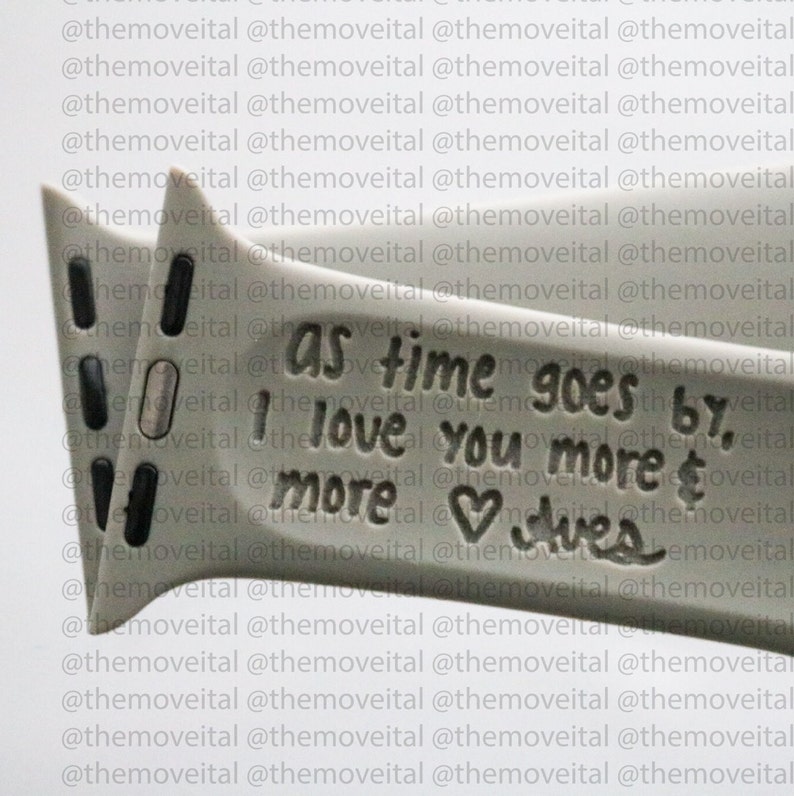 以下が含まれることがあります： ハートと「As time goes by, I love you more & more」という刻印が施されたグレーの金属製のブレスレットです。