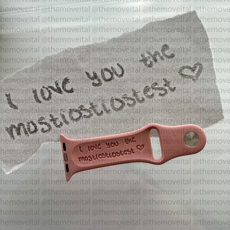 以下が含まれることがあります： 「I love you the mostiostostest」というテキストとハートマークが書かれたピンクのシリコン製腕時計バンド