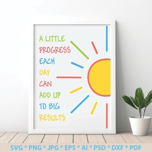 May include: A white framed print with a yellow sun and colorful rays. The text reads "A little progress each day can add up to big results".