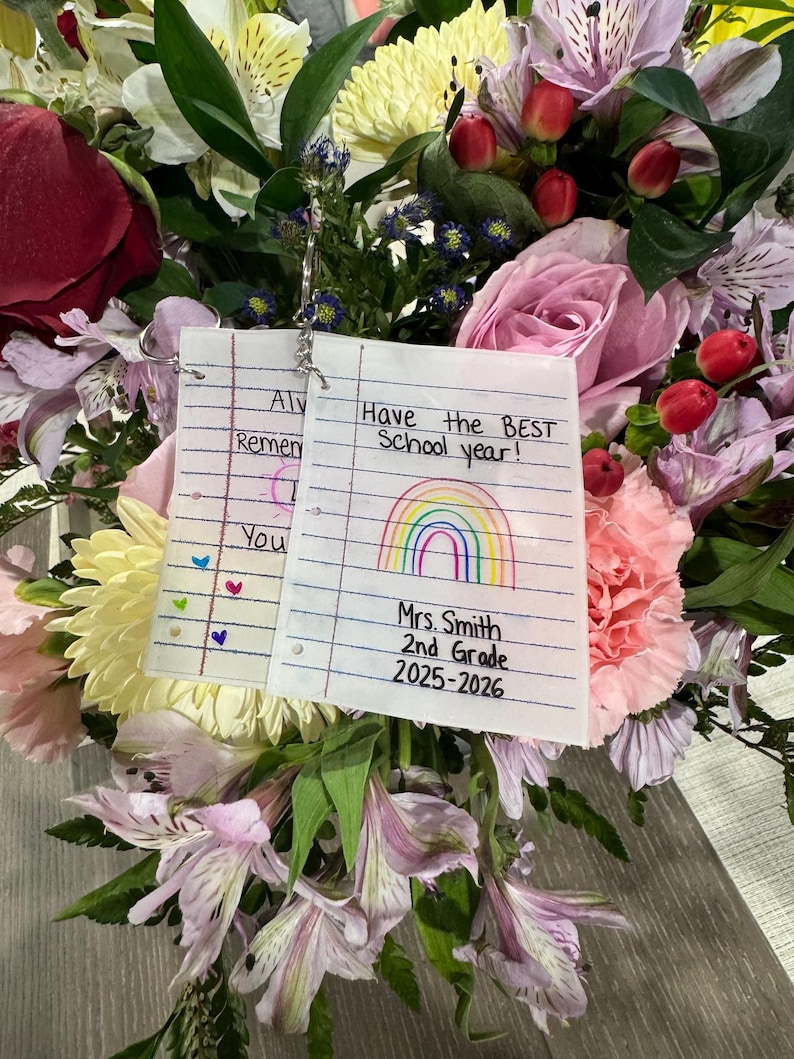 Puede incluir: Un vibrante ramo de flores, que incluye rosas, lirios y claveles, con una nota escrita a mano que dice "Have the BEST School year!" y "Mrs. Smith 2nd Grade 2025-2026". Las flores son en tonos de rosa, rojo, amarillo y morado.
