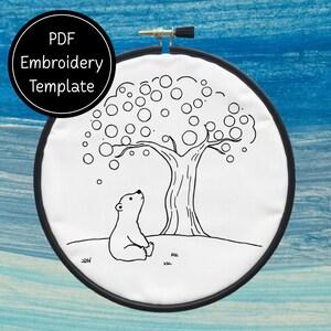 May include: Black and white embroidery design of a polar bear looking up at a tree with round fruit. The design is on a white hoop.