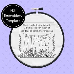 May include: A black and white embroidery template in a round hoop. The design features clothing hanging on a clothesline with the text "She is clothed with strength & dignity; she can laugh at the days to come. Proverbs 31:25" and "PDF Embroidery Template".