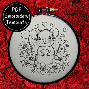 May include: Black and white embroidery design of a mouse holding a heart surrounded by flowers. The design is on a white fabric background and is in a round embroidery hoop. The text "PDF Embroidery Template" is in the upper left corner of the image.