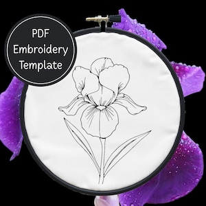 Peut inclure: Un modèle de broderie d'iris en noir et blanc dans un cercle. Le texte "PDF Embroidery Template" est dans un cercle noir. Le fond présente des pétales de fleurs violettes avec des gouttelettes d'eau.