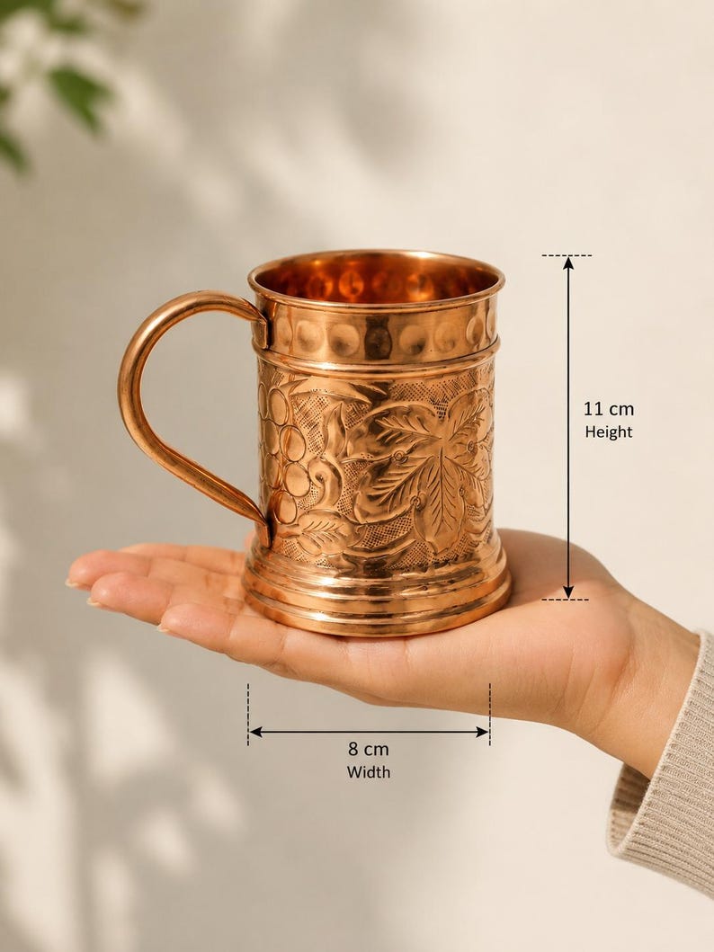 May include: A copper mug with a curved handle and embossed grape and leaf patterns on the exterior. The mug features a smooth rim and base, with a height of 11 cm and a width of 8 cm as indicated by the measurement markers on the image.