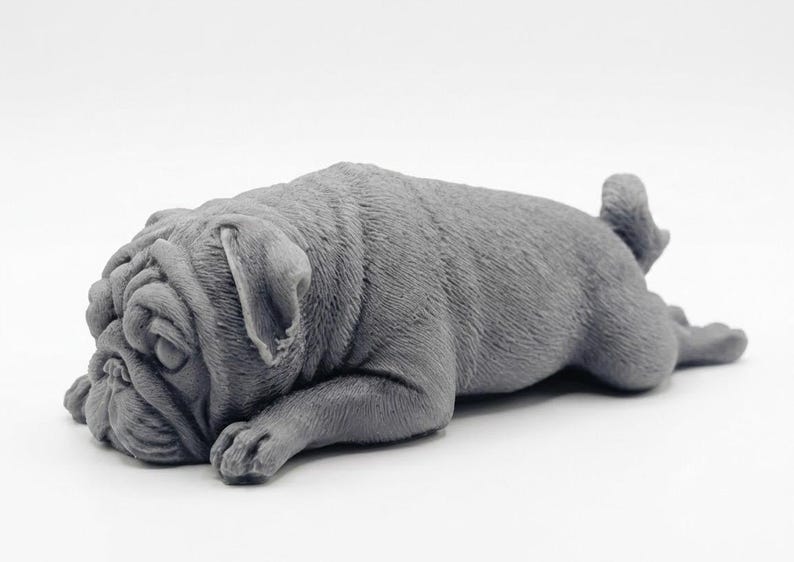 A detailed handmade vegan soap gift, sculpted in the shape of a pug dog lying flat on its stomach in a sleeping position, showing realistic skin folds and fur texture