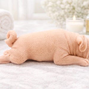 handmade vegan soap in the shape of a realistic sleeping pug dog lying flat, showing detailed wrinkles and fur texture, displayed in a spa-like setting with a candle and lavender.