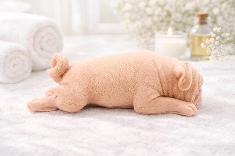 handmade vegan soap in the shape of a realistic sleeping pug dog lying flat, showing detailed wrinkles and fur texture, displayed in a spa-like setting with a candle and lavender.