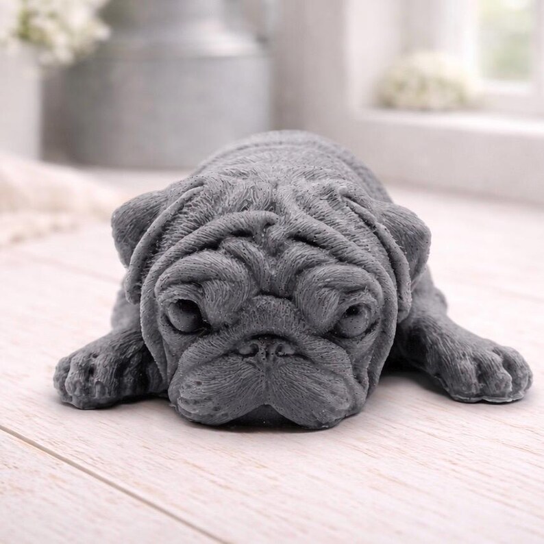 A detailed handmade vegan soap gift, sculpted in the shape of a pug dog lying flat on its stomach in a sleeping position, showing realistic skin folds and fur texture