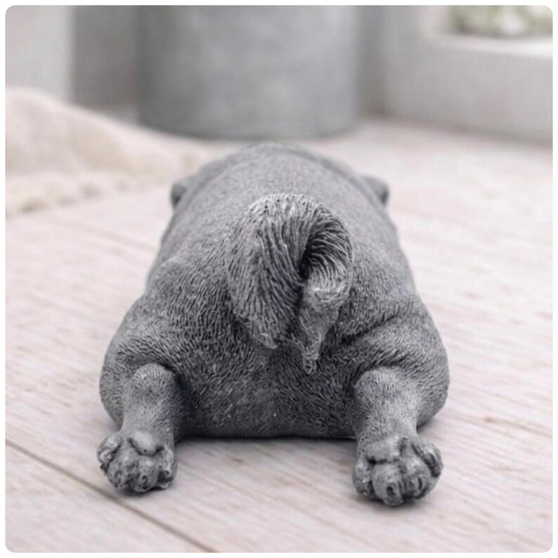 A detailed handmade vegan soap gift, sculpted in the shape of a pug dog lying flat on its stomach in a sleeping position, showing realistic skin folds and fur texture