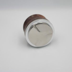 以下が含まれることがあります： 3 本の爪のデザインが施された、銀色と茶色のコーヒータンパーです。