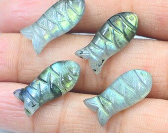 Puede incluir: Cuatro tallas de peces de labradorita verde y azul iridiscente. Los peces están tallados con un patrón detallado y tienen un acabado liso y pulido.