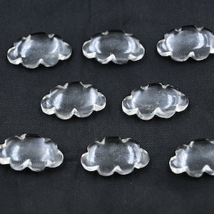 Könnte beinhalten: Acht durchsichtige, wolkenförmige Dekorationsobjekte aus Glas auf schwarzem Hintergrund.