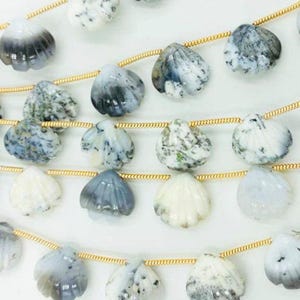 Op de afbeelding: Een streng witte en grijze edelsteen kralen in de vorm van schelpen. De kralen zijn geregen aan een gouden ketting.