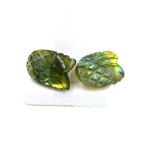 May include: Two carved labradorite gemstone pineapple pendants with iridescent green, blue, and gold hues.