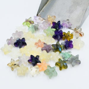 Puede incluir: Surtido de cuentas de piedras preciosas en forma de estrella en varios colores, incluyendo morado, verde, amarillo y naranja. Las cuentas están hechas de piedras naturales y tienen un acabado pulido.