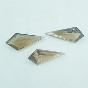 May include: Three faceted, clear, smoky quartz gemstones in a kite shape.
