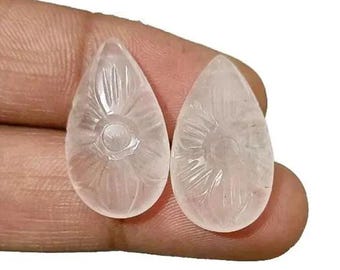 Puede incluir: Dos piedras de cuarzo talladas en forma de lágrima transparentes con un diseño floral. Las piedras son translúcidas y tienen un acabado liso y pulido.