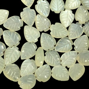 May include: A collection of white, carved leaf-shaped beads. The beads are made of a translucent material and have a delicate, intricate design.