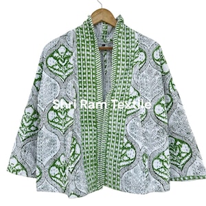 May include: A white and green patterned jacket with a V-neck design. The jacket is hanging on a wooden hanger. The jacket has a floral pattern and the text "Shri Ram Textile".