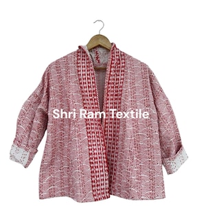 May include: A red and white patterned jacket with a wave-like design. The jacket has a white interior and trim, and the text "Shri Ram Textile" is visible. The jacket is hanging on a wooden hanger.