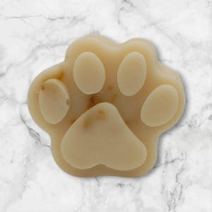 May include: A light beige paw-shaped soap bar with a textured surface.