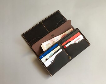 May include: A brown leather wallet with multiple card slots and a billfold. The wallet is open and has several cards and bills inside.
