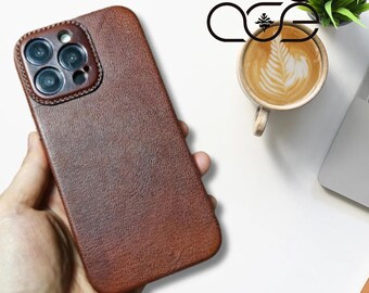 May include: A brown leather phone case with a camera cutout. The case has a textured surface and a subtle sheen.