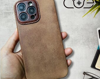 May include: A brown leather phone case with a camera cutout. The case has a textured surface and a stitched edge.