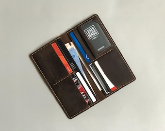 May include: A brown leather wallet with multiple card slots and a billfold. The wallet is open and has several cards and cash inside. The wallet has a small card slot with the text "Laser Mads Member" printed on it.