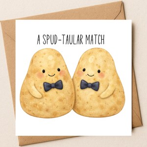 May include: A square greeting card featuring an illustration of two tan potatoes with pink cheeks and black bow ties. The text above the potatoes reads A SPUD-TAULAR MATCH in black capital letters. The card is placed on a brown paper envelope.